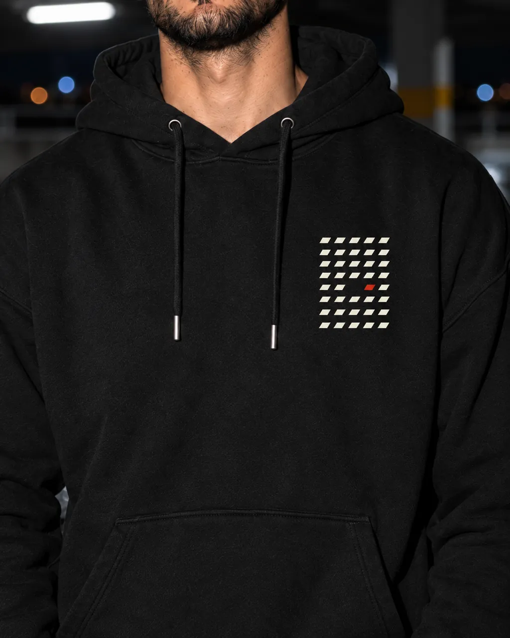 Aralık Premium Siyah Hoodie: göğüsteki baskı yakından, gece boş bir otoparkta