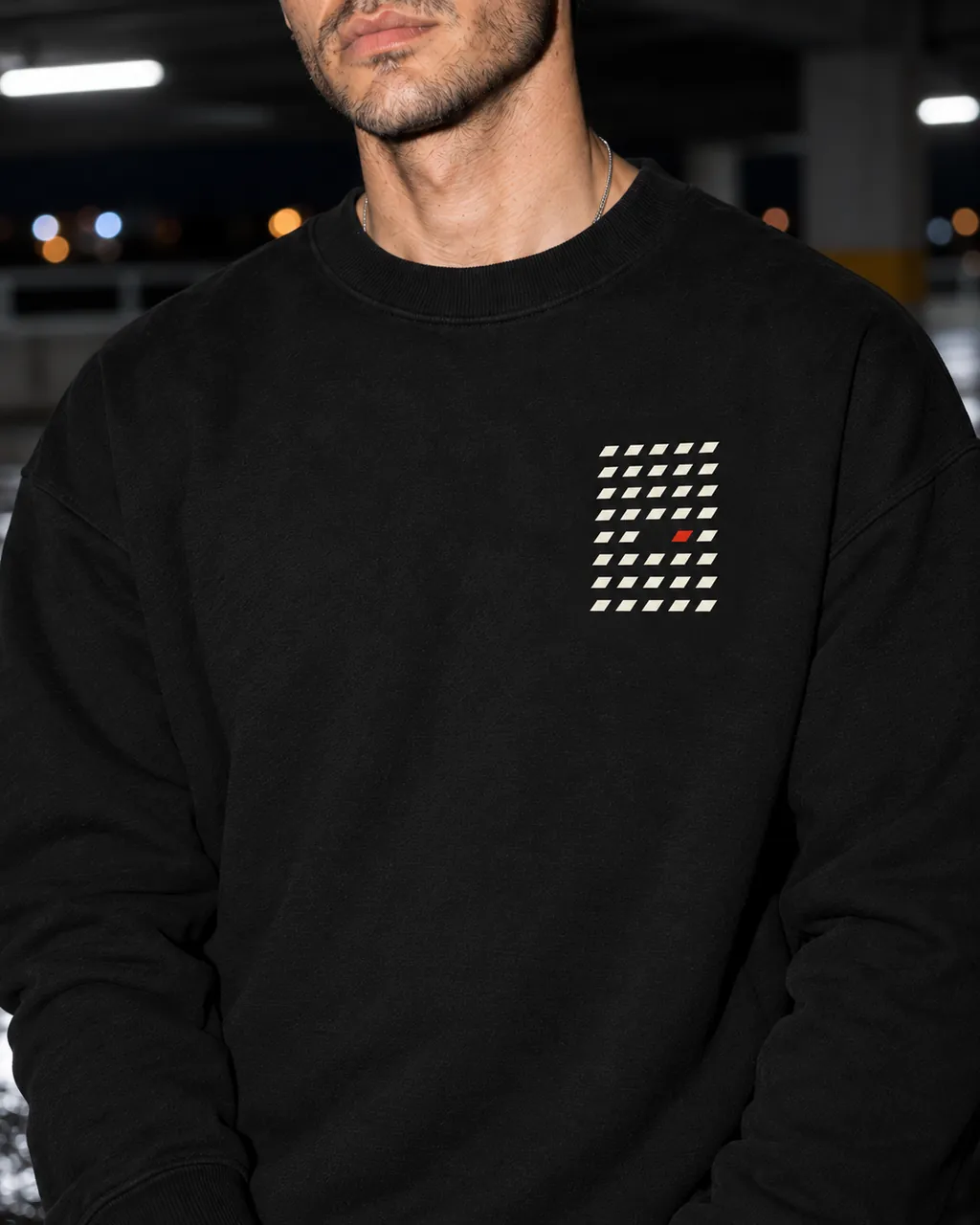 Aralık Premium Siyah Sweatshirt: göğüsteki baskı yakından, gece boş bir otoparkta