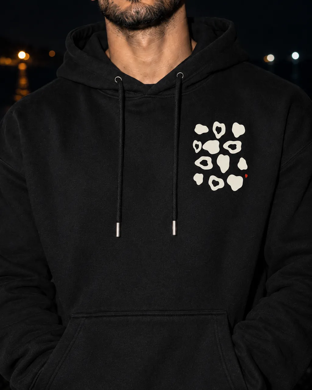 Çakıltaşı Premium Siyah Hoodie: göğüsteki baskı yakından, gece siyah çakıllı bir sahilde