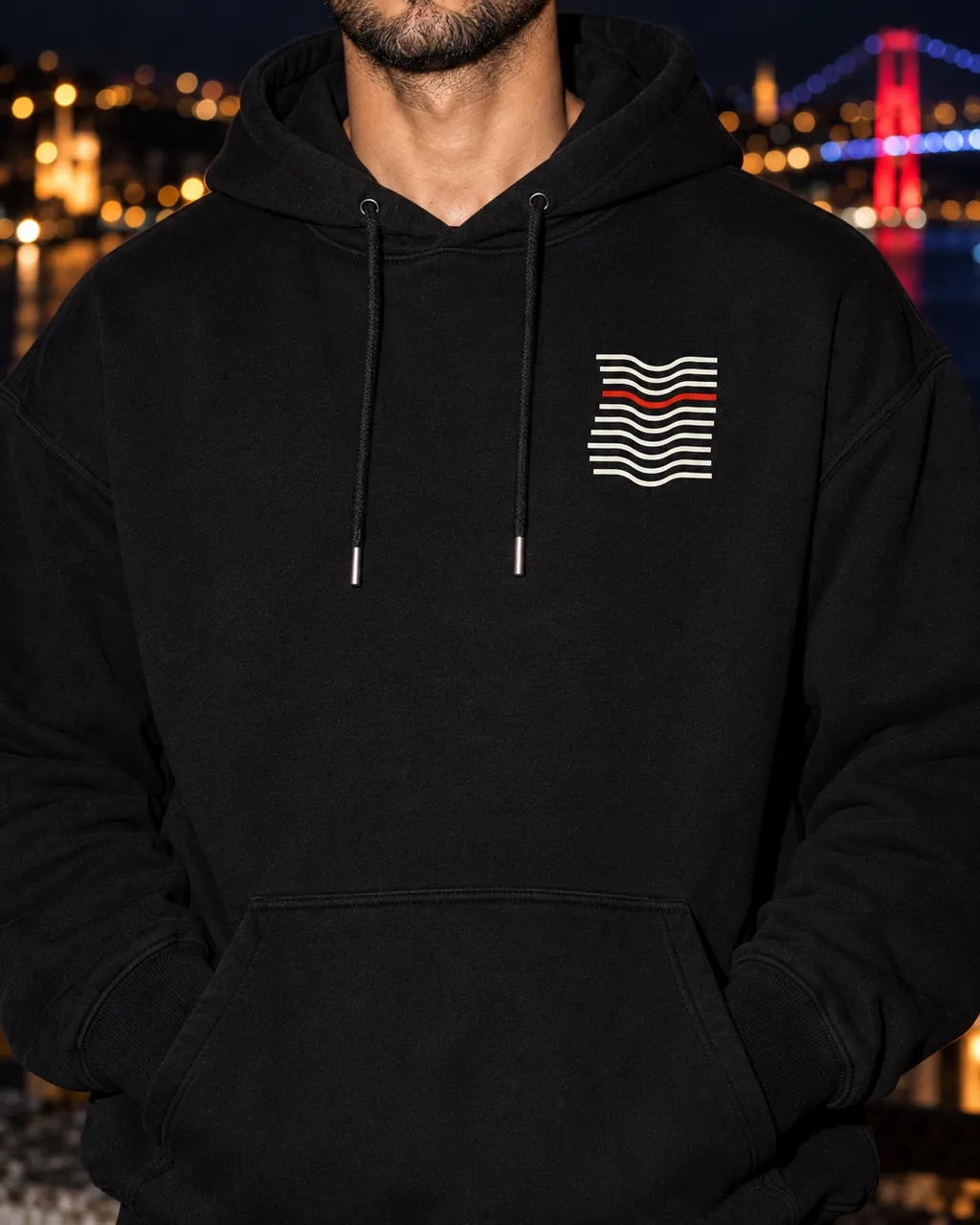 Kıvrım Premium Siyah Hoodie: göğüsteki baskı yakından, gece Boğaz'a bakan bir çatıda