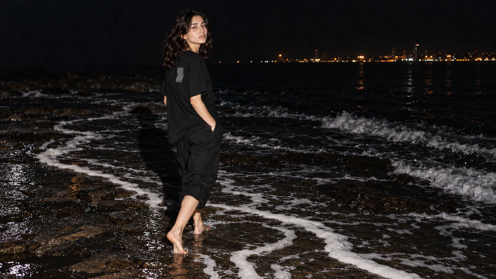 Kavis desenli siyah tişört giyen bir model, gece dalga çizgisinde