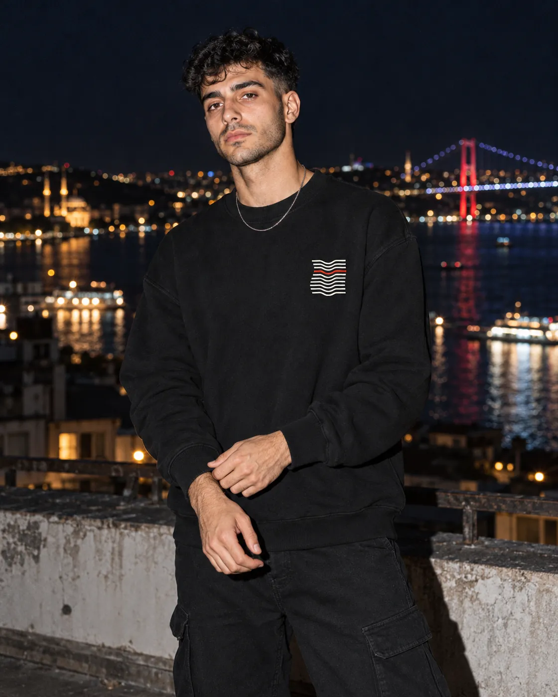 Kıvrım Premium Siyah Sweatshirt: model üzerinde, gece Boğaz'a bakan bir çatıda