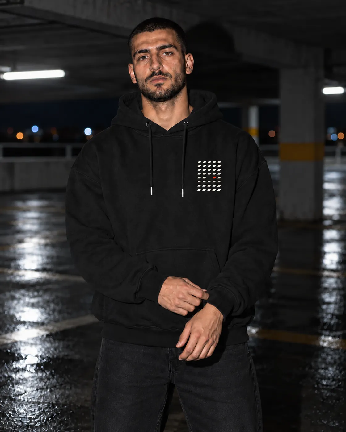 Aralık Premium Siyah Hoodie: model üzerinde, gece boş bir otoparkta