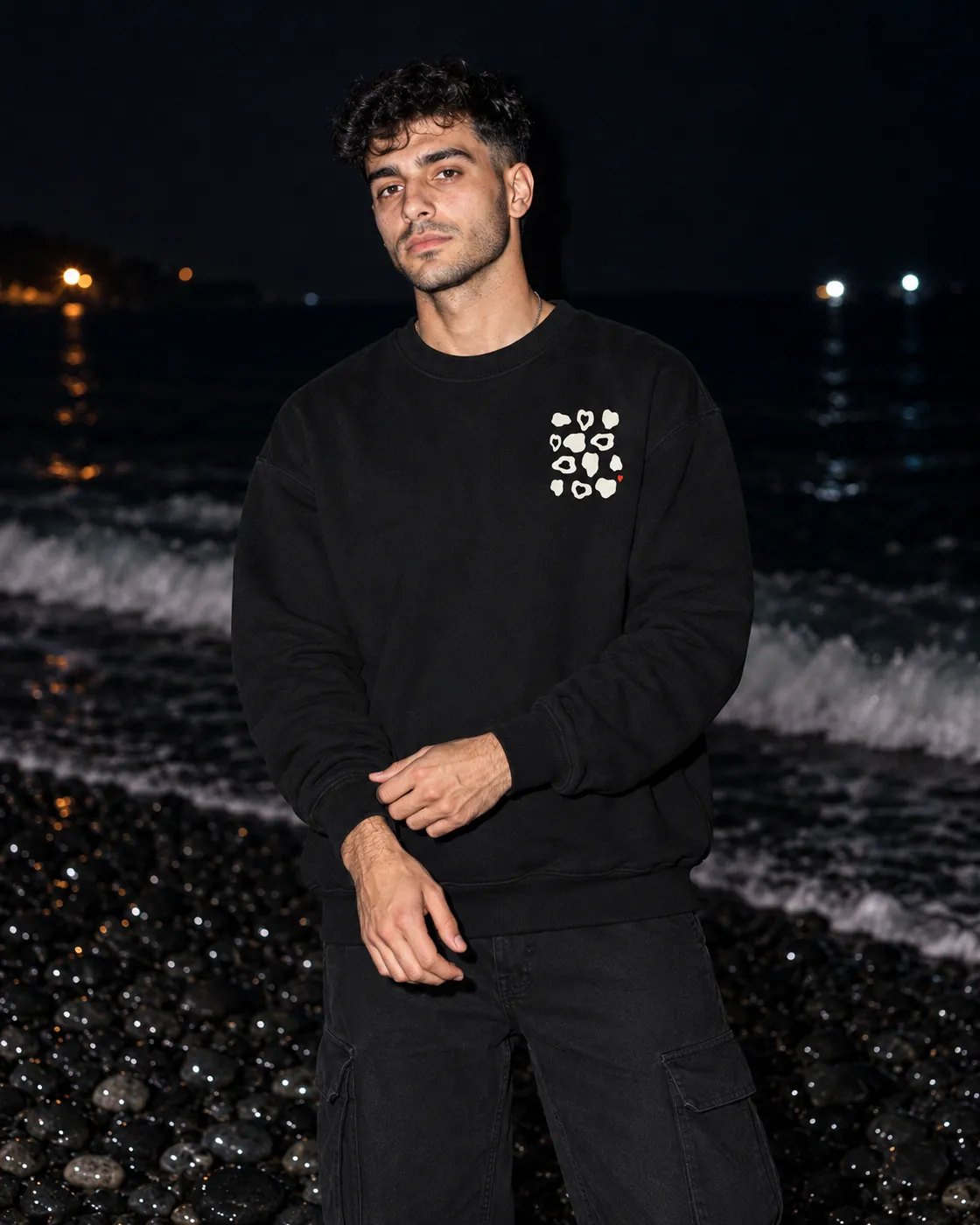 Çakıltaşı Premium Siyah Sweatshirt: model üzerinde, gece siyah çakıllı bir sahilde