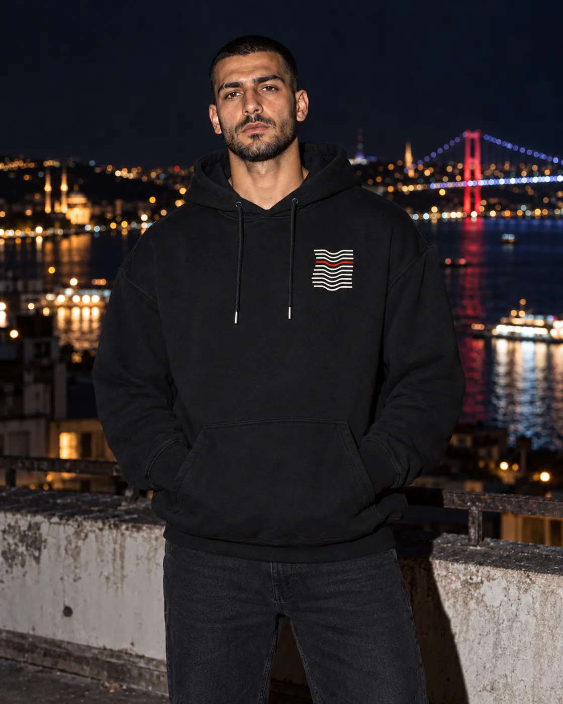 Kıvrım Premium Siyah Hoodie: model üzerinde, gece Boğaz'a bakan bir çatıda
